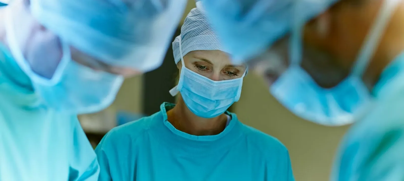 Surgical team in masks, caps and gowns at work in an operating theatre